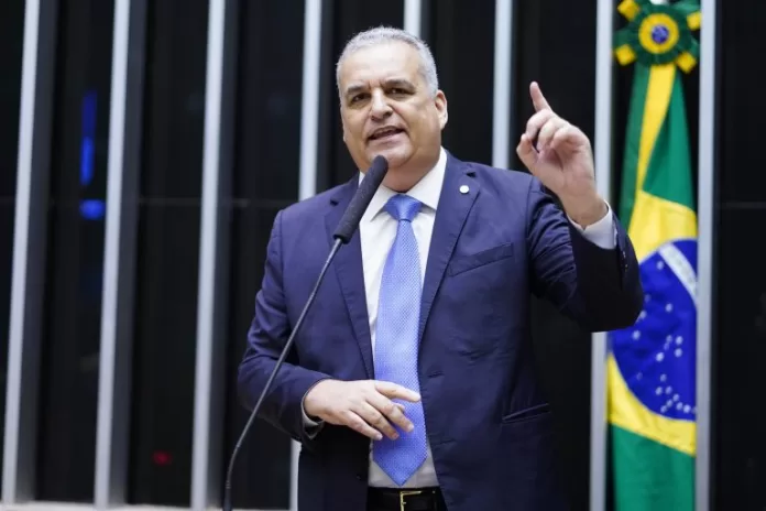 Deputado Alfredo Gaspar fala ao microfone. Ele é um homem branco, usa terno azul escuro e está com o dedo em riste