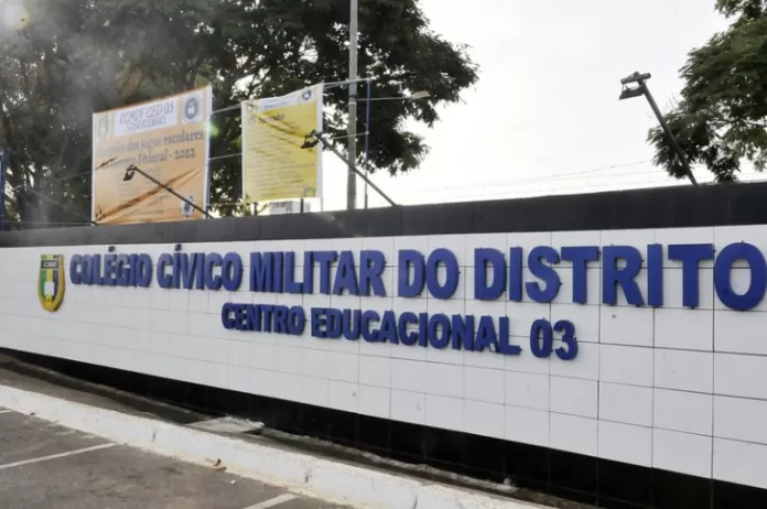 Muro de escola na cor branca com letras azuis onde se lê: Colégio cívico militar do Distrito Federal