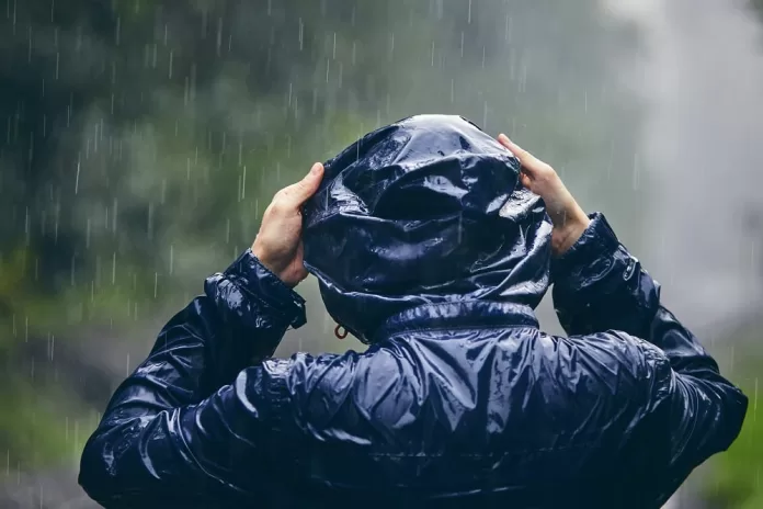 homem com capuz em chuva forte