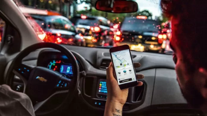 Pessoa com aplicativo do Uber aberto em celular dentro de carro