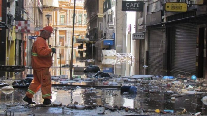 homem andando em Porto Alegre limpando ruas após enchente