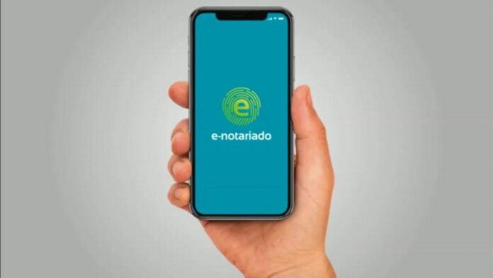 Imagem mostra mão segurando celular com app do e-notariado