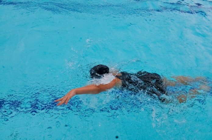 Uma criança nada na piscina