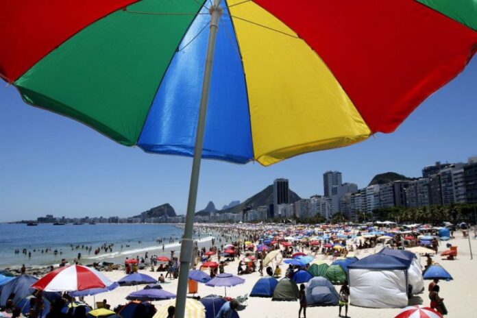 Praia no Rio de Janeiro com muitas pessoas aproveitando um dia de sol