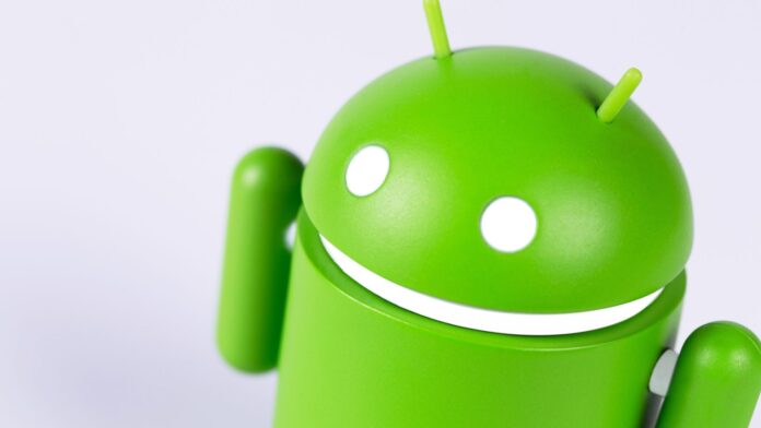 Robozinho do Android meio de lado e próximo à câmera em fundo branco