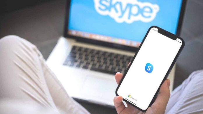 Mulher usando smartphone com aplicativo Skype.